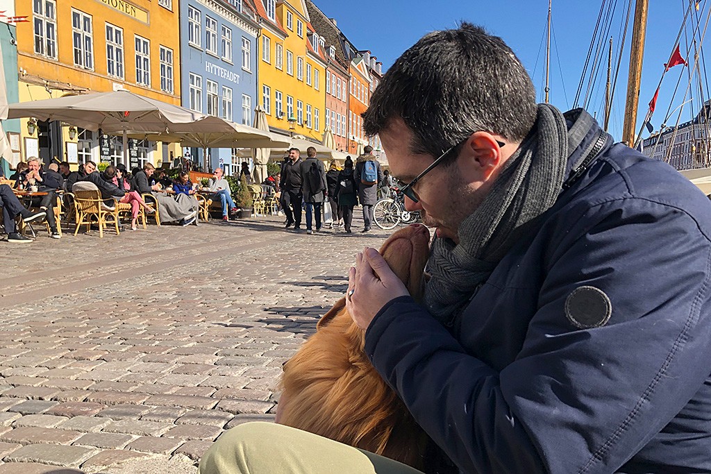 Edisons sitzt zwischen Stephans Beinen am Nyhavn und streckt seinen Kopf gen Stephans Kopf